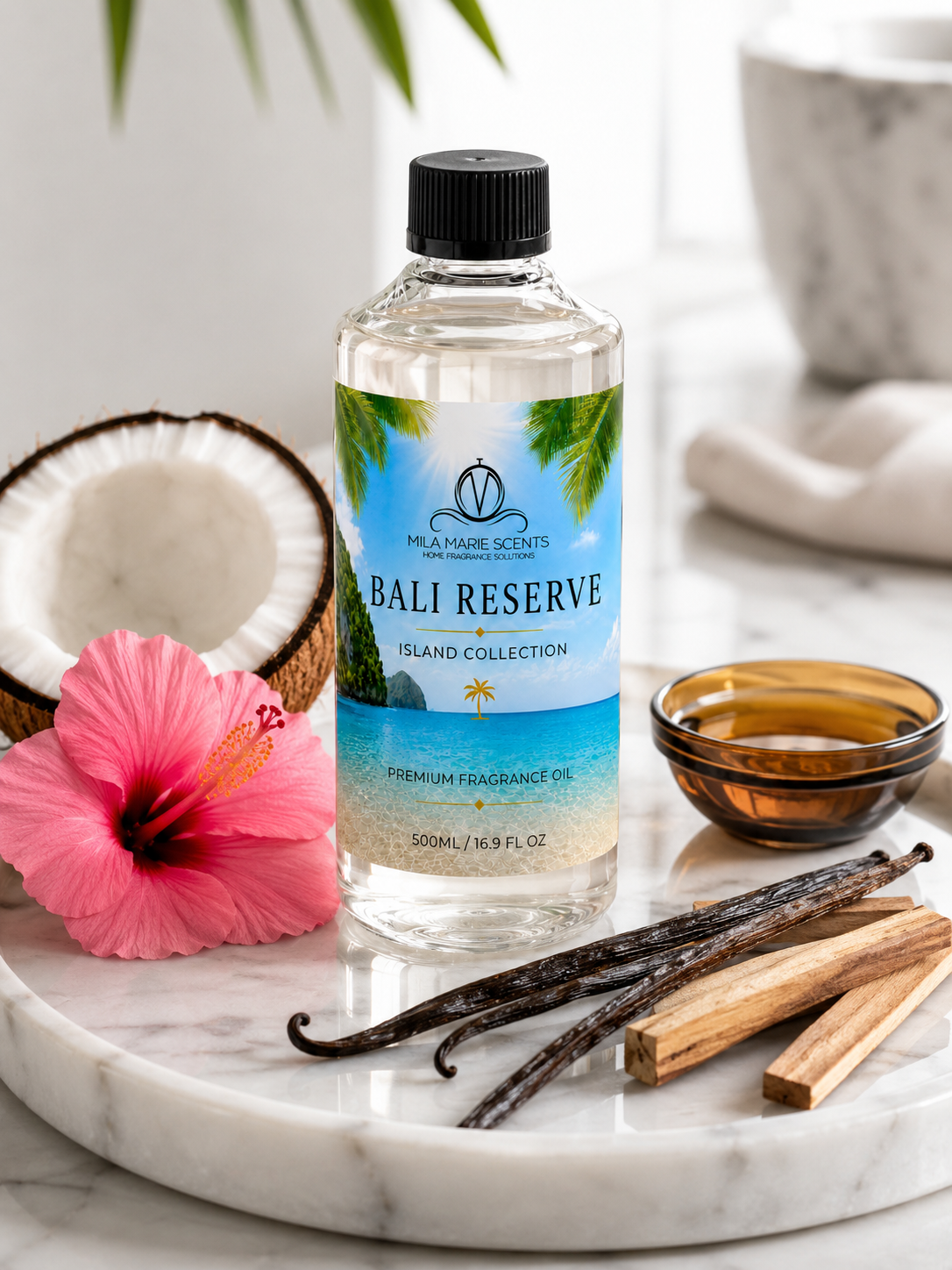Bottle of Bali Reserve fragrance oil on a marble surface with vanilla beans, a pink flower, and a coconut.