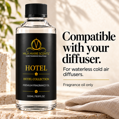 
A bottle of Mila Marie Scents Hotel Collection fragrance oil on a stone surface with a beige cloth and soft background shadows. Text on the right reads 'Compatible with your diffuser.