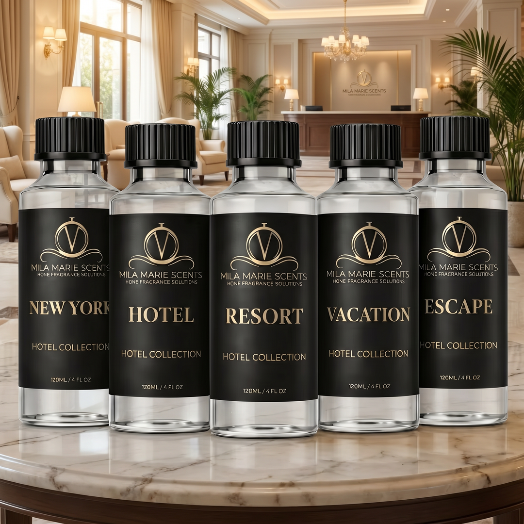 Five bottles of Mela Marie Scents home fragrance solution on a marble table with a luxurious hotel lobby in the background.