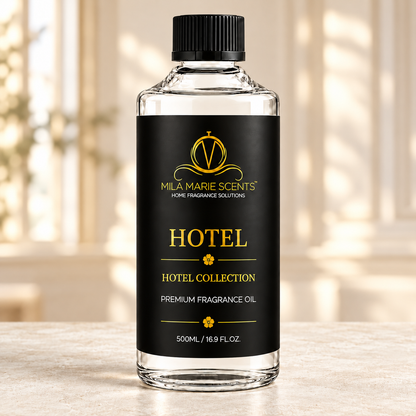 
A 500ml bottle of Milá Marie Scents Hotel Collection fragrance oil, featuring a black label with gold lettering and a black ribbed cap, set against a softly blurred warm-toned background.