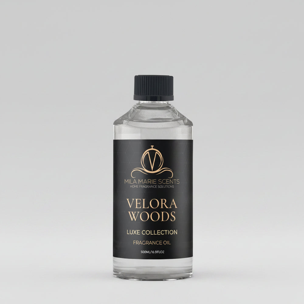 Bottle of Velora Woods fragrance oil on a wooden surface with a blurred office background